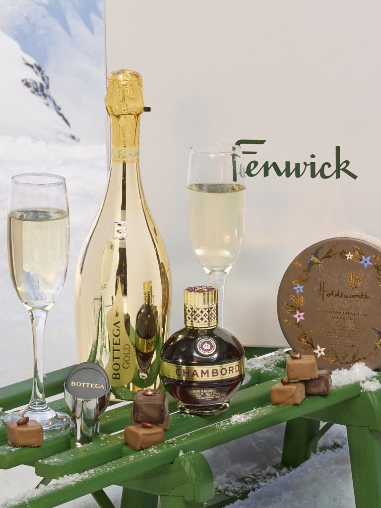 Bottega Gold prosecco, Chambord liqueur, champagne flutes and chocolates displayed in a festive Fenwick setting.