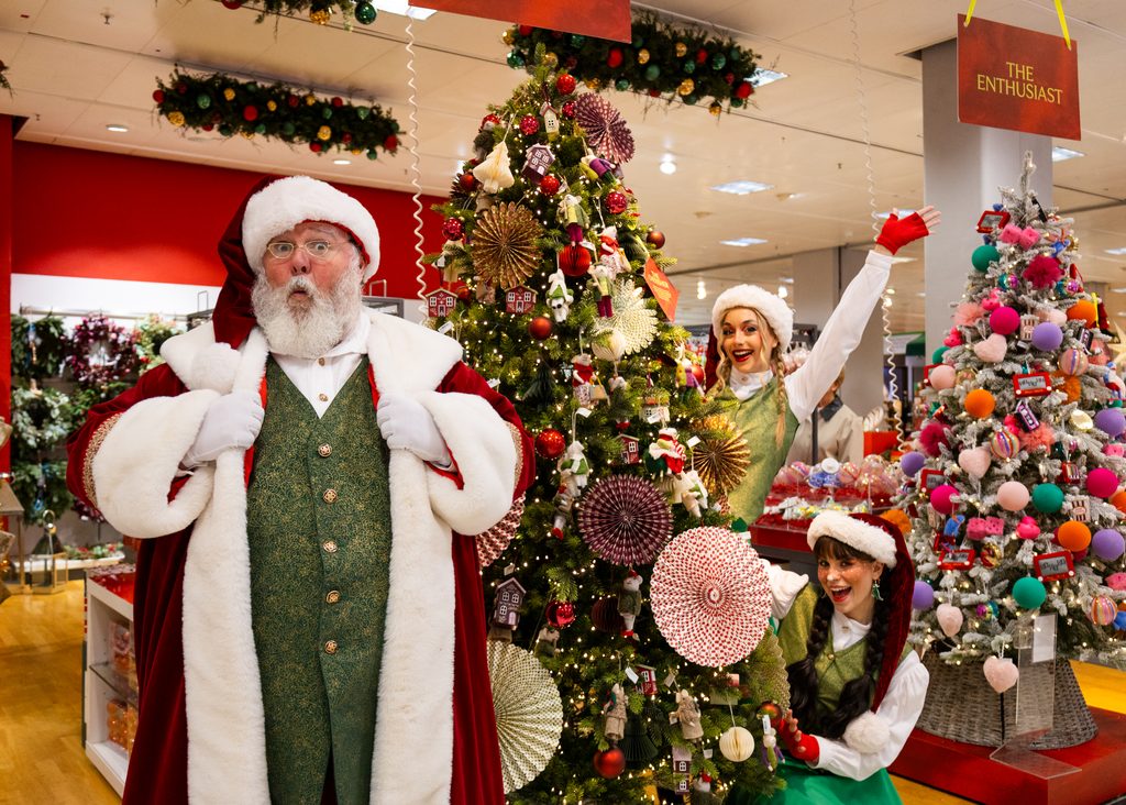 Santa Claus and his elves surrounded by colourful Christmas decorations and gifts at Eldon Square in Newcastle.
