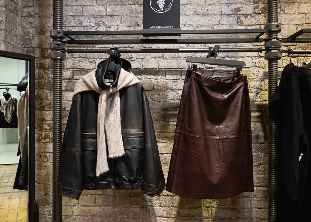 Leather handbags and autumn/winter clothing displayed against an exposed brick wall at AllSaints in Eldon Square Newcastle.