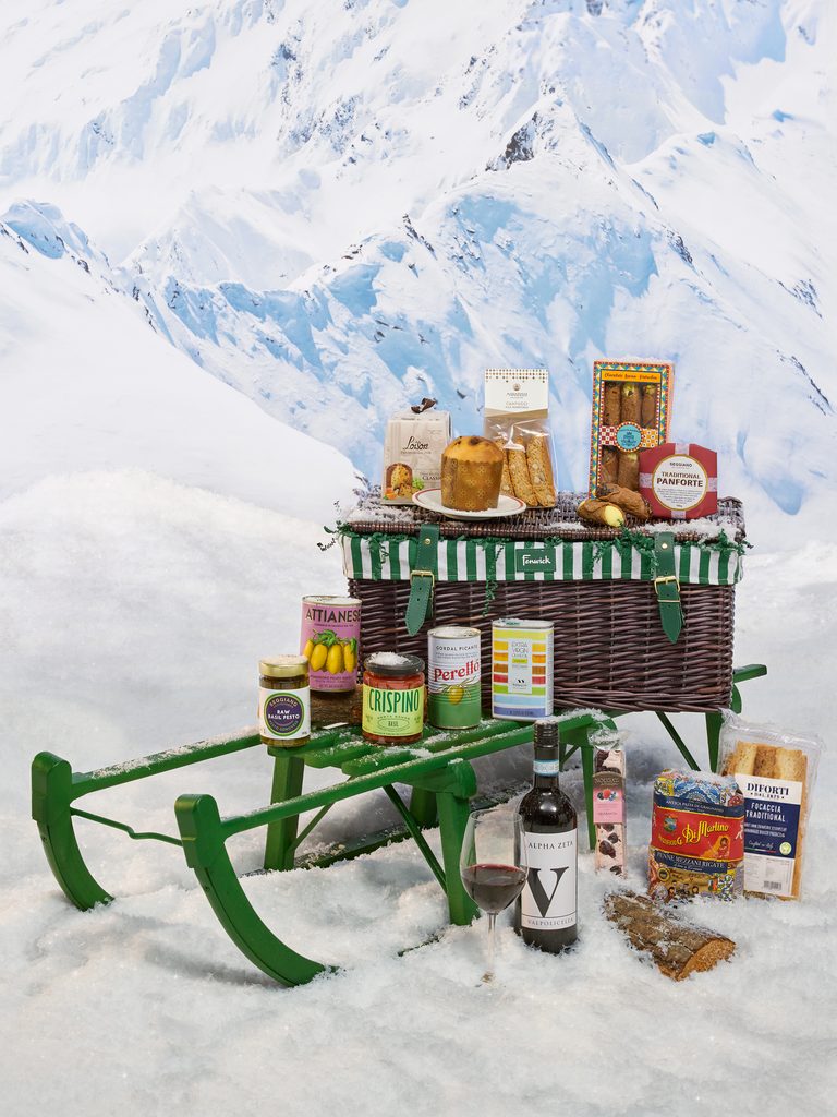 Fenwick's Italian Christmas Hamper featuring pasta, Italian biscuits, olive oil, preserves and red wine in a festive alpine setting.